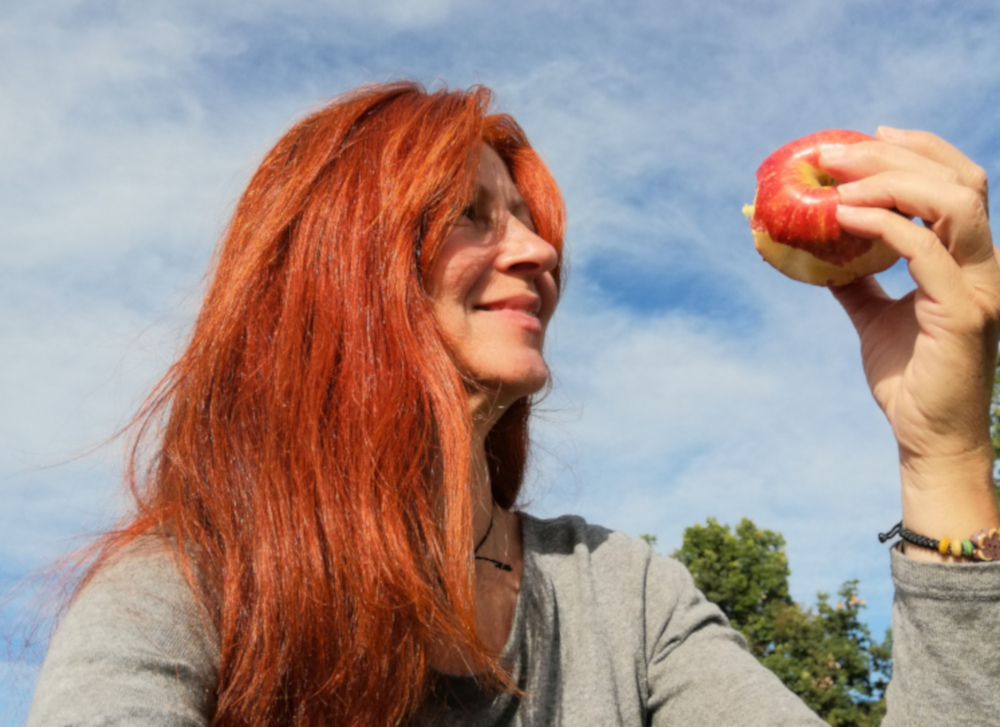 Frau sieht einen Apfel an, den sie in der Hand hält