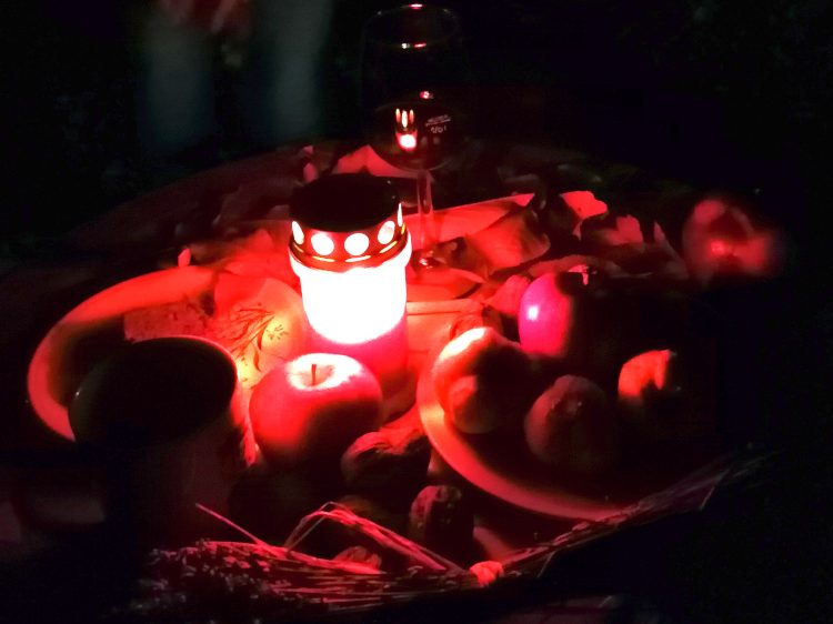 Tisch im Dunkeln mit Äpfel und brennender Kerze