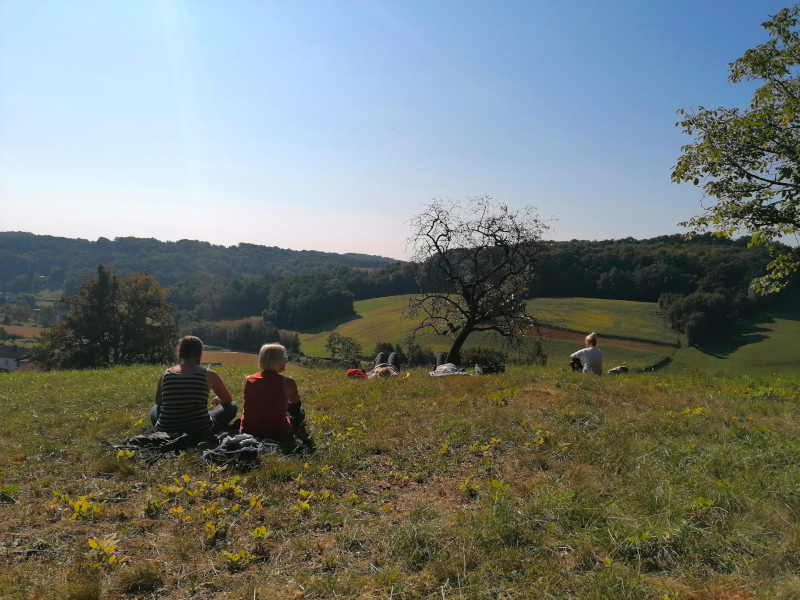 Zwei Frauen sitzen auf einer Wiese und blicken in die Ferne.