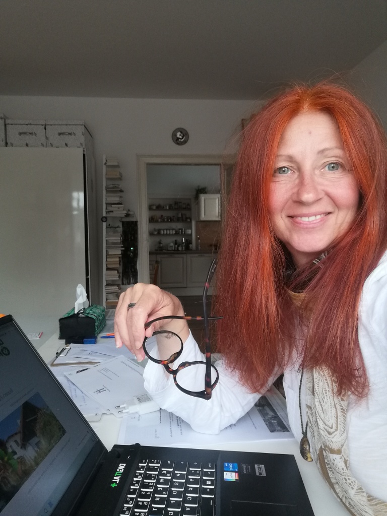 Karin Hartmann mit Brille in der Hand vor einem Notebook
