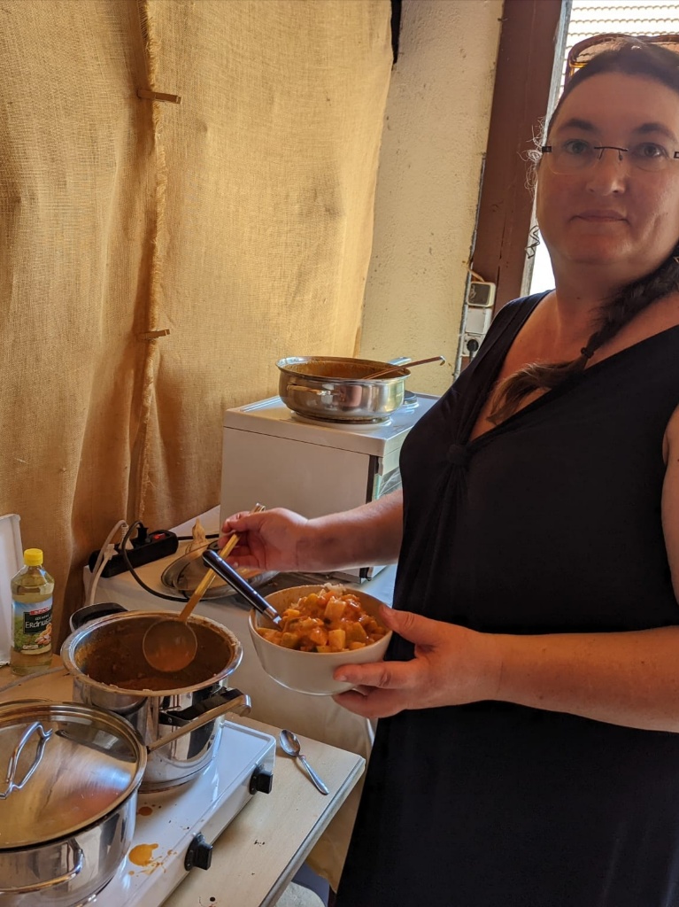 Eine Frau am Herd, die sich mit einem Schöpflöffel ein Eintopfgericht in eine Suppenschüssel schöpft