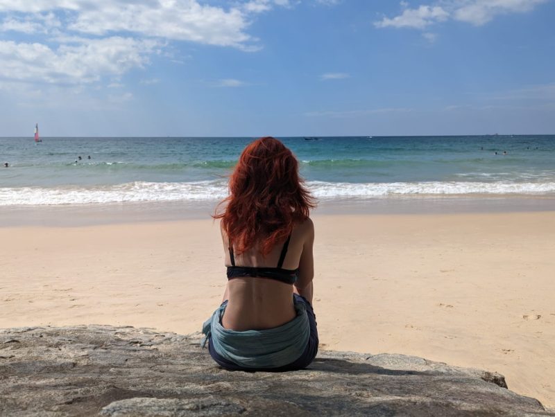 Frau von hinten, sitzend am Strand
