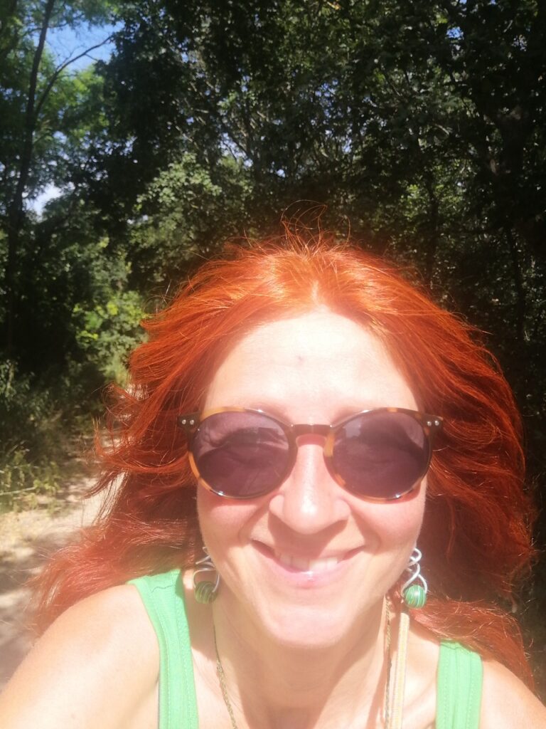 Karin Selfie beim Radfahren, mit fliegendem rotem Haar und Sonnenbrille