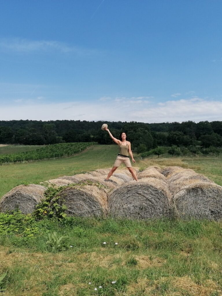Claudia auf Strohballen, mit Weingärten und Leithaberg im Hintergrun