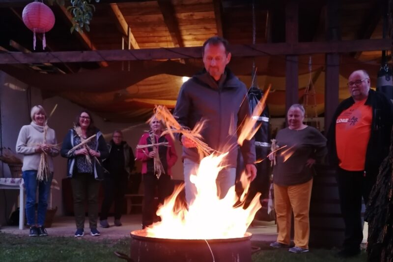 Ein Mann wirft seine Kornpuppe ins Feuer
