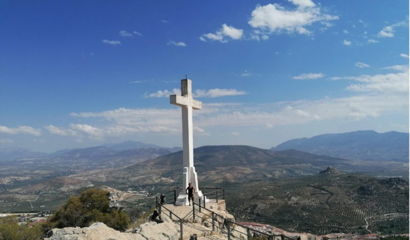 Großes weißes Kreuz auf der Festung von Jaén - im Hintergrund herrliche Aussicht auf Hügel mit Olivenhainen.