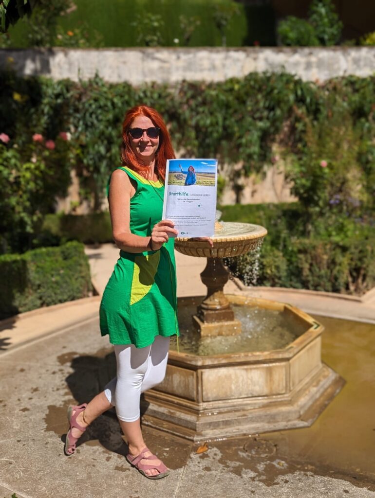 Karin bei einem Springbrunnen im Garten der Alhambra mit dem Freebie in der Hand