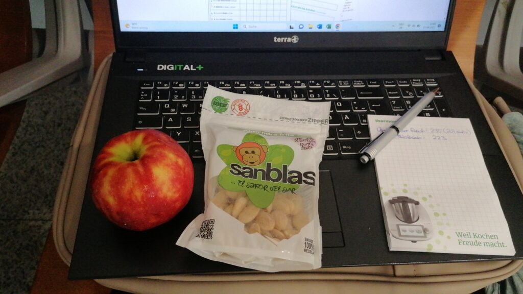1 Apfel und 1 Packung Mandeln liegen auf einer Laptop-Tastatur