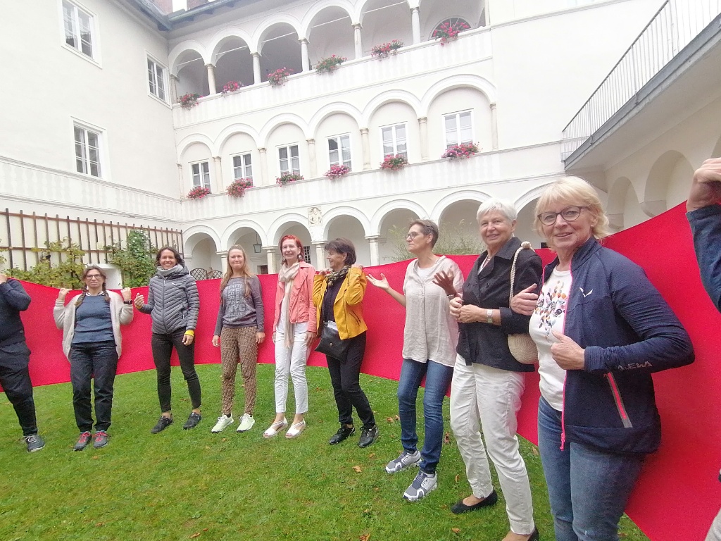 Menschen stehen im Kreise eines roten Bandes