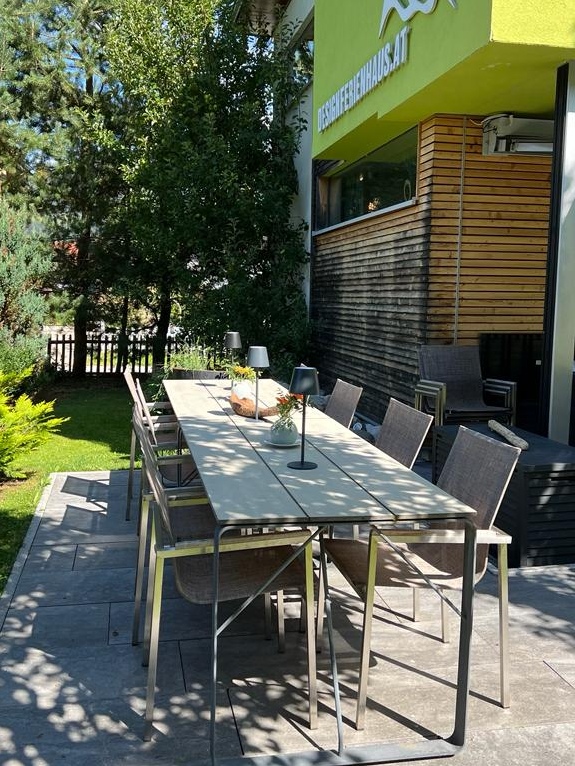 Langer Gartentisch mit acht Stühlen auf der Gartenterrasse des Design Ferienhauses