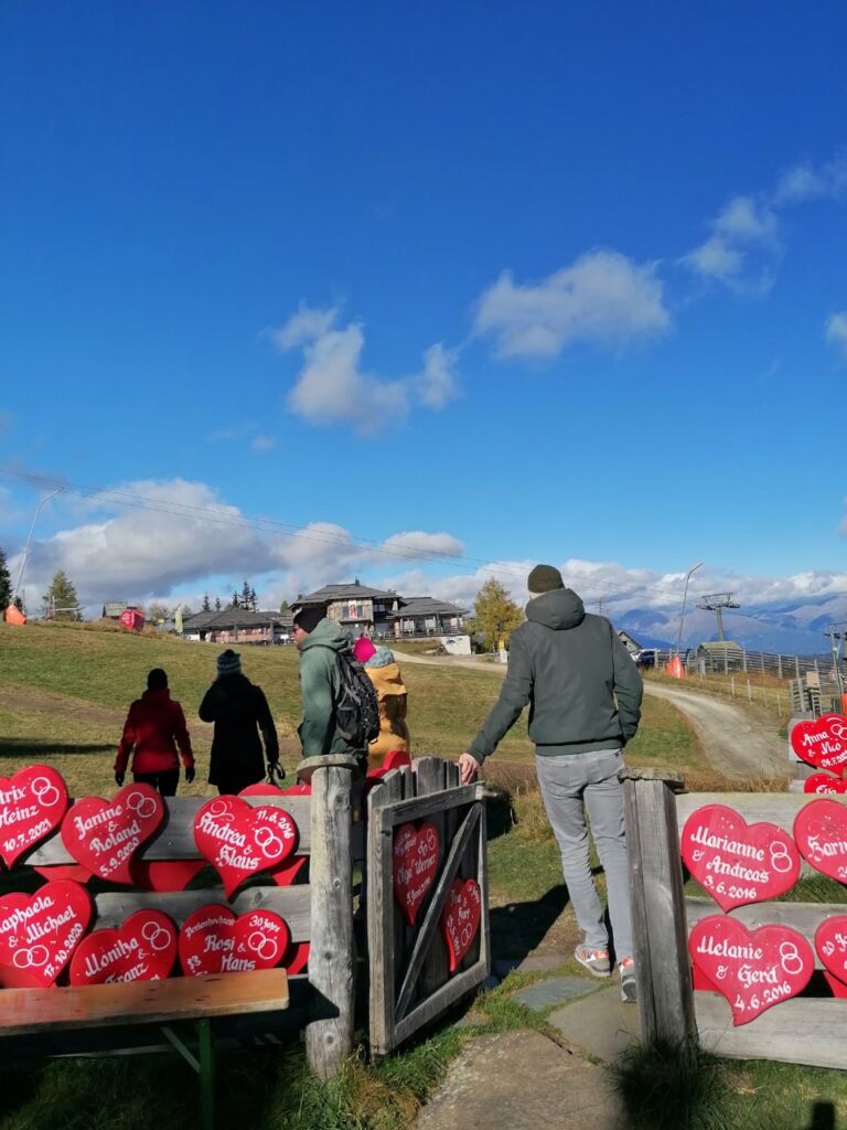 Wandergruppe von hinten beim Verlassen der Herzerlkapelle bei der Gamskogelhütte. Strahlend blauer Himmel.