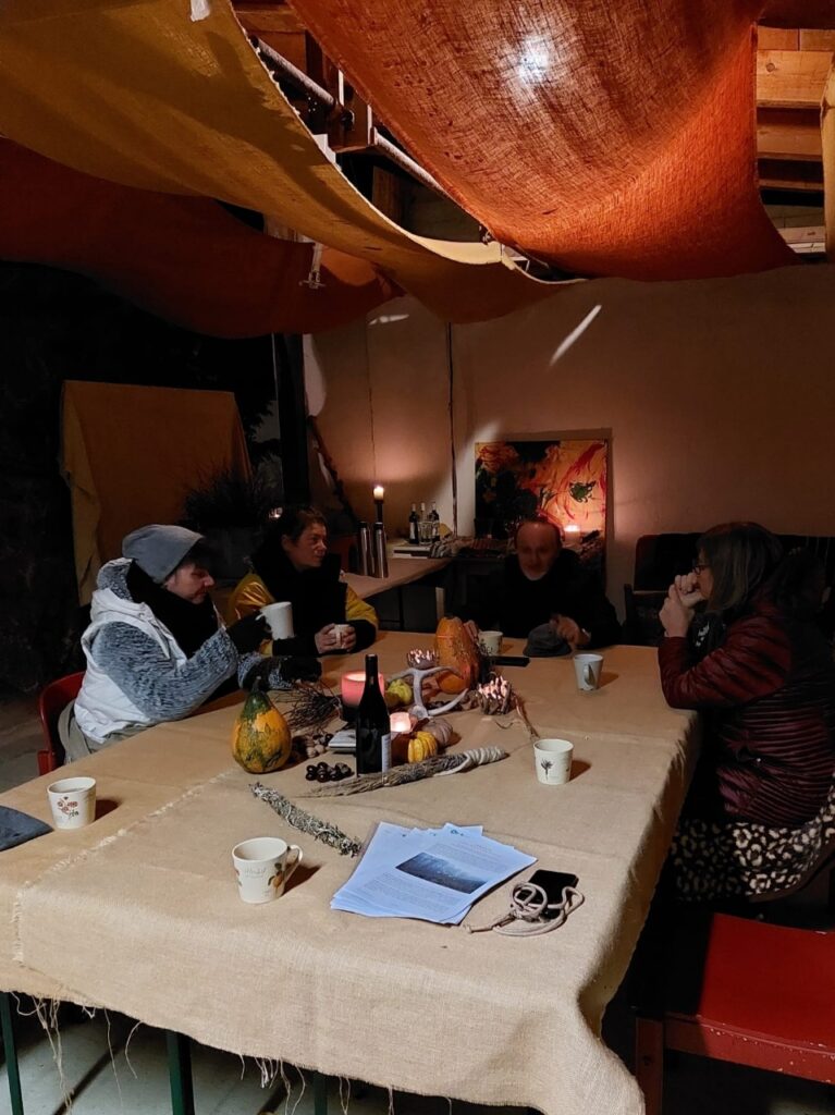 4 Personen, die im Halbdunkeln an einem Tisch mit Kerzen sitzen.