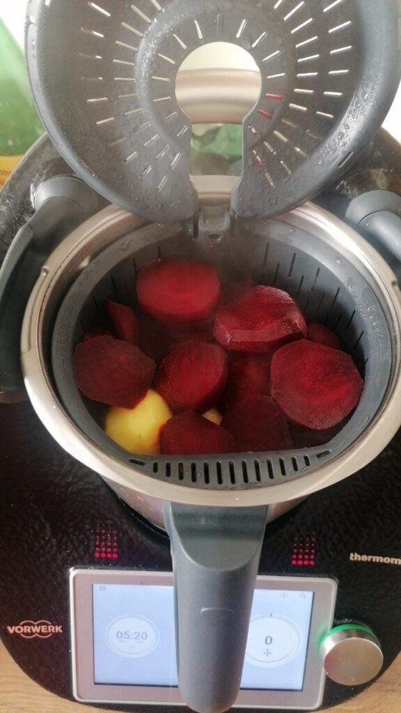 Geöffneter Thermomix mit roten Rüben im Garkörbchen. Darunter sind Kartoffeln.