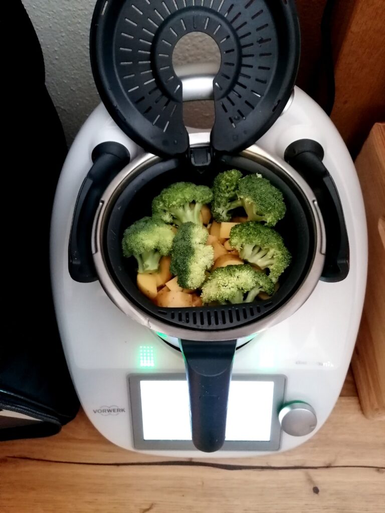 Geöffneter Thermomix mit Brokkoli und Kartoffeln im Garkörbchen