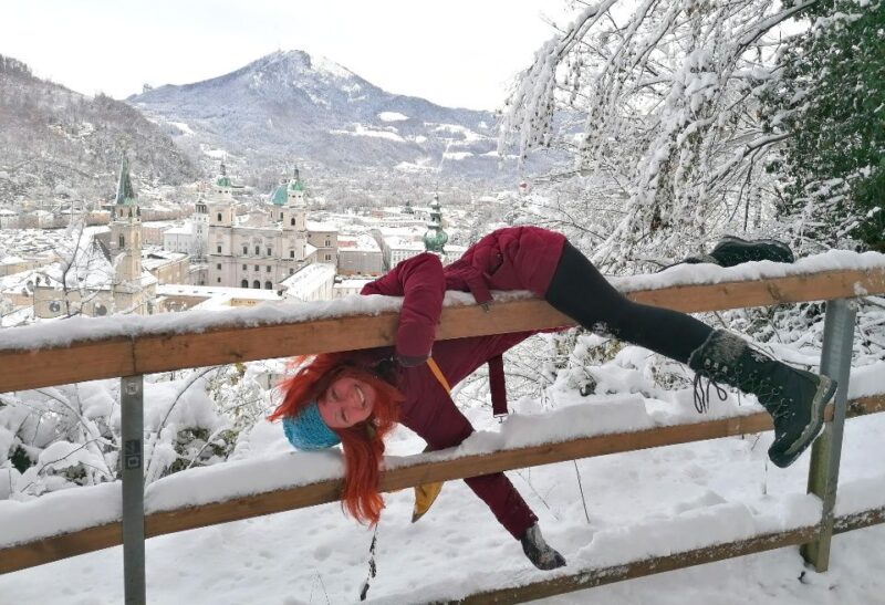 Karin am Gelaender haengend ueber den verschneiten Daechern von Salzburg