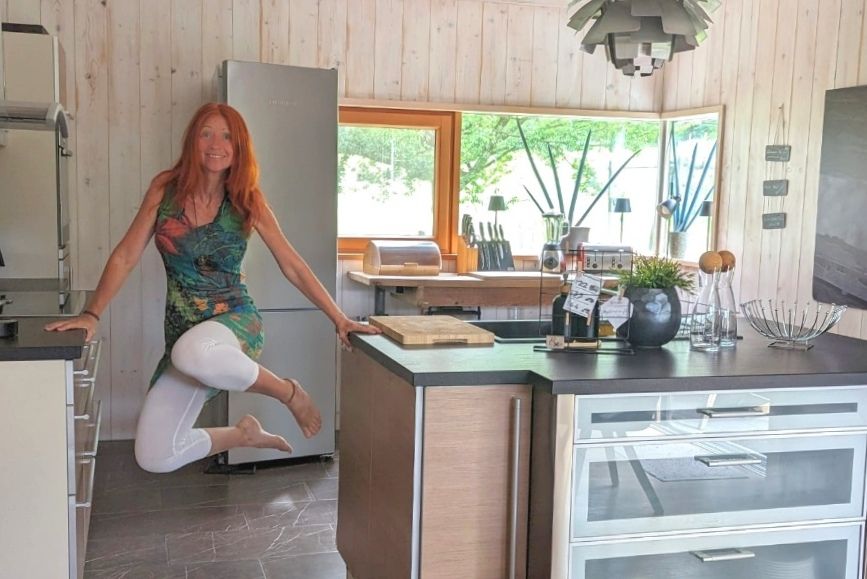 Karin turnt in der Küche mit angezogenen Beinen