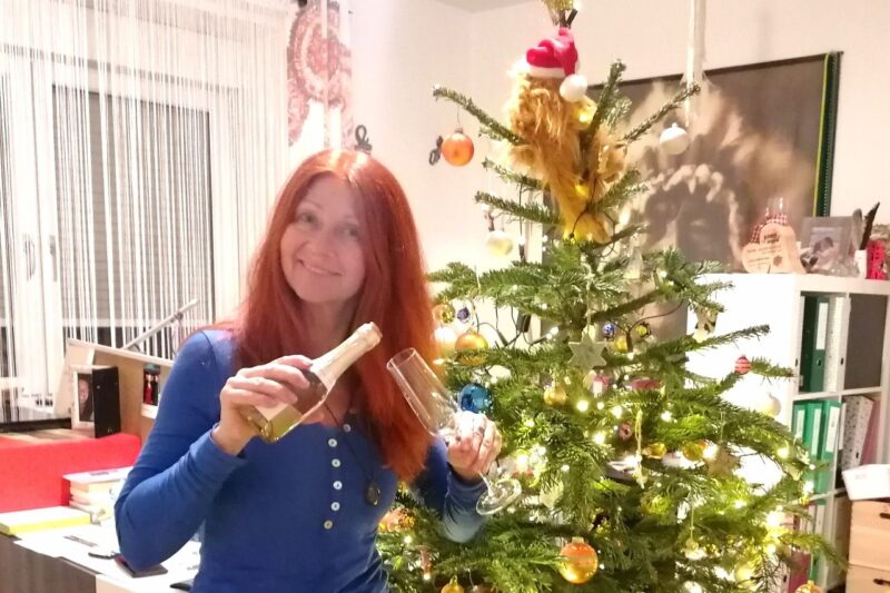 Karin vor dem Christbaum mit Sektglas und kleinem Sektflascherl