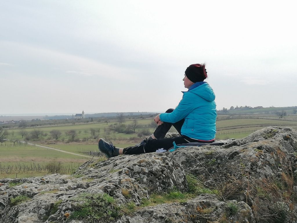 Frau sitzt am Felsen und blickt in die Ferne.