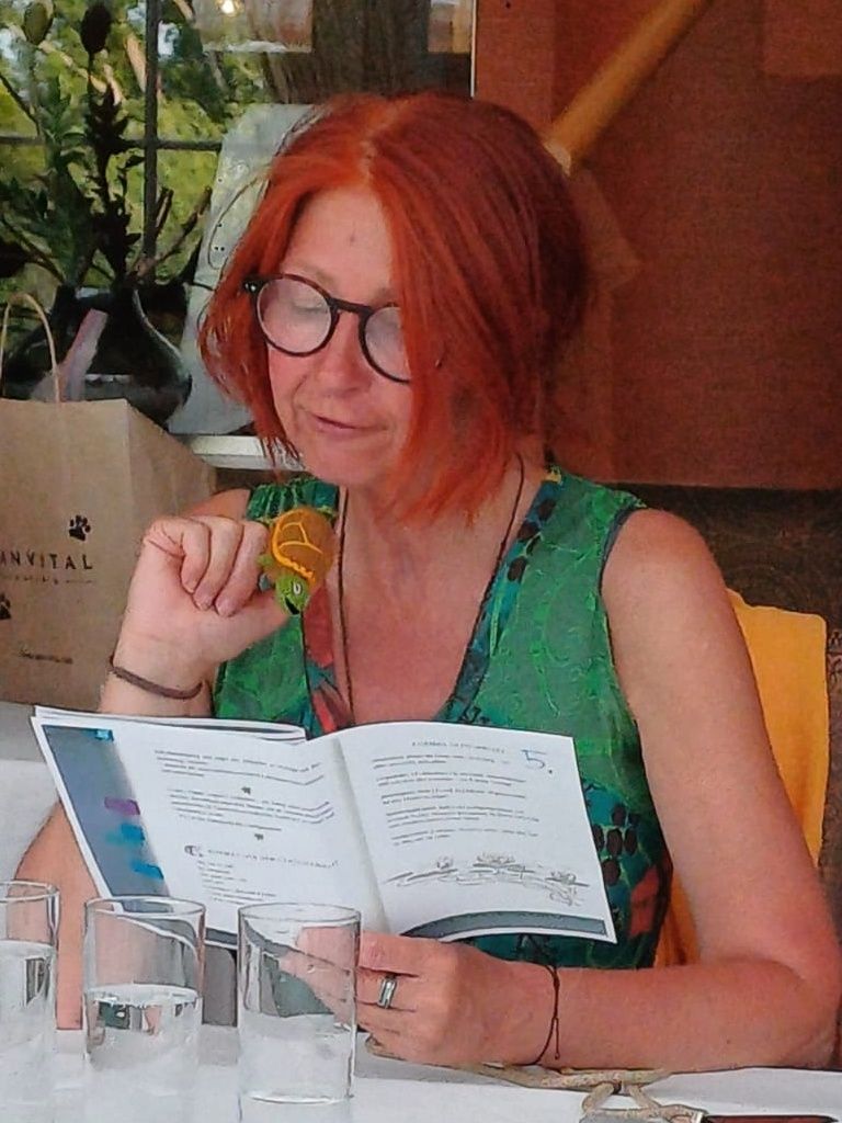 Karin mit Brille beim Vorlesen einer Geschichte, und einer kleinen Schildkröten-Fingerpuppe am rechten Zeigefinger