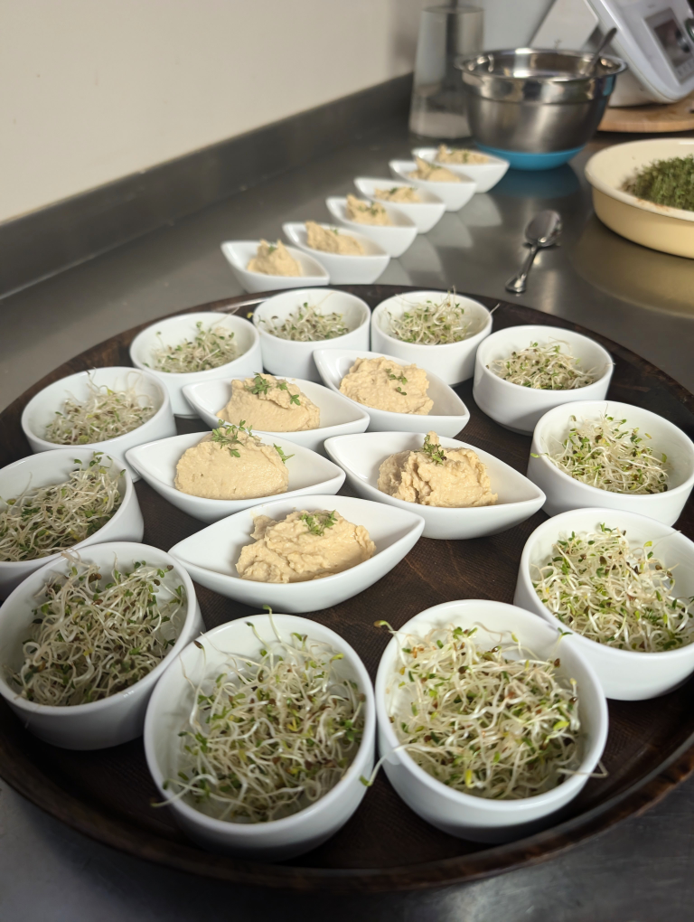 Tablet mit kleinen Schüsselchen, gefüllt mit Humus und Sprossen