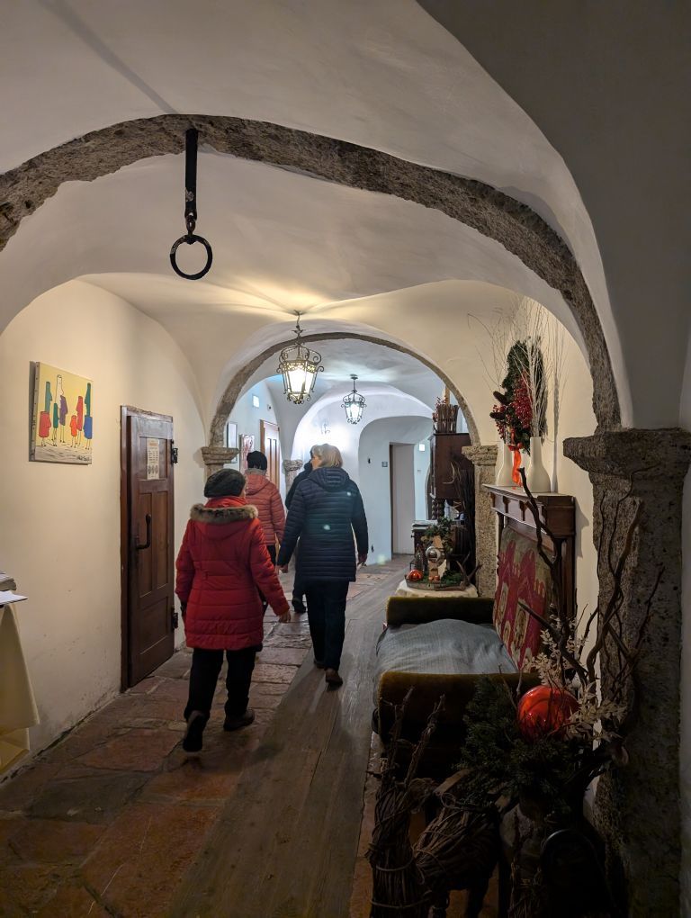 3 Menschen von hinten im inneren eines Hauses mit Deckengewölbe