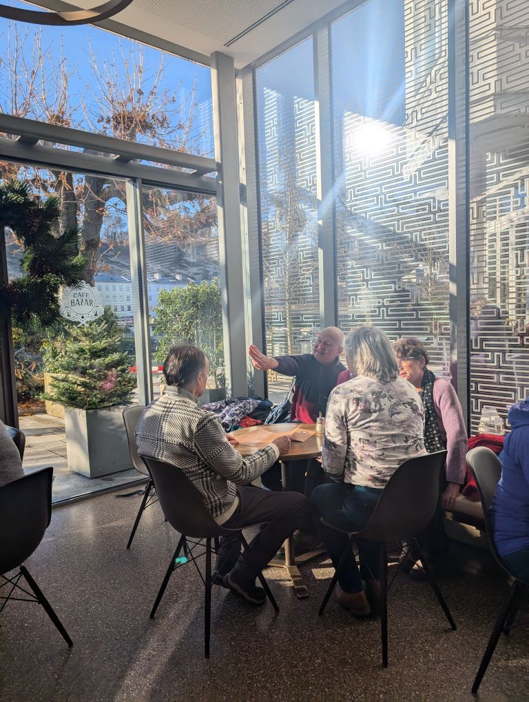 Fastengruppe sitzt entspannt an einem Tisch in einem lichtdurchfluteten Raum