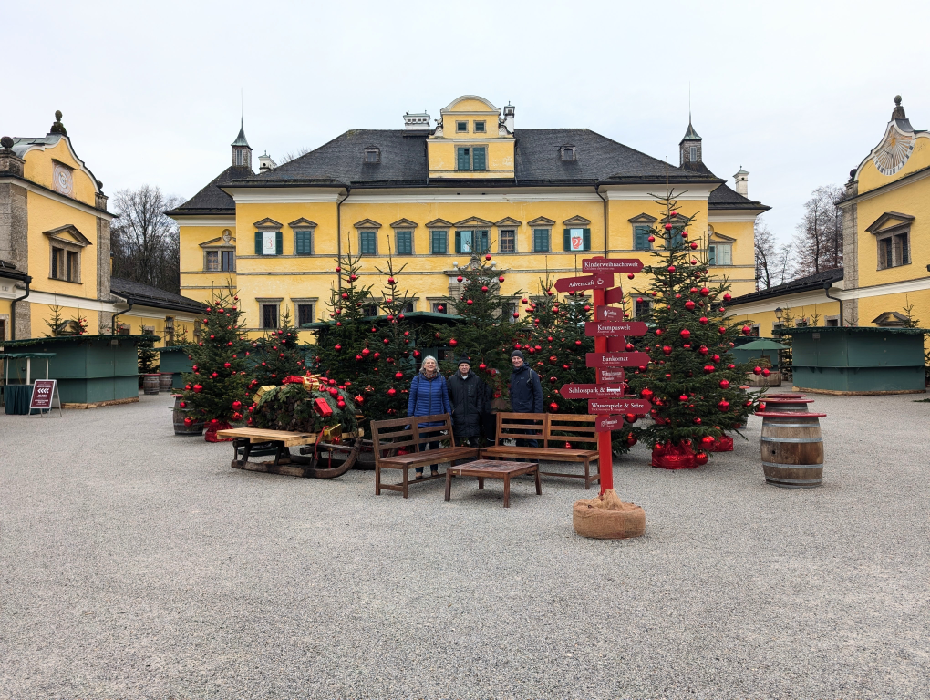 Schloss Hellbrunn von vorne, davor Weihnachtsbäume und 3 Fastenteilnehmer