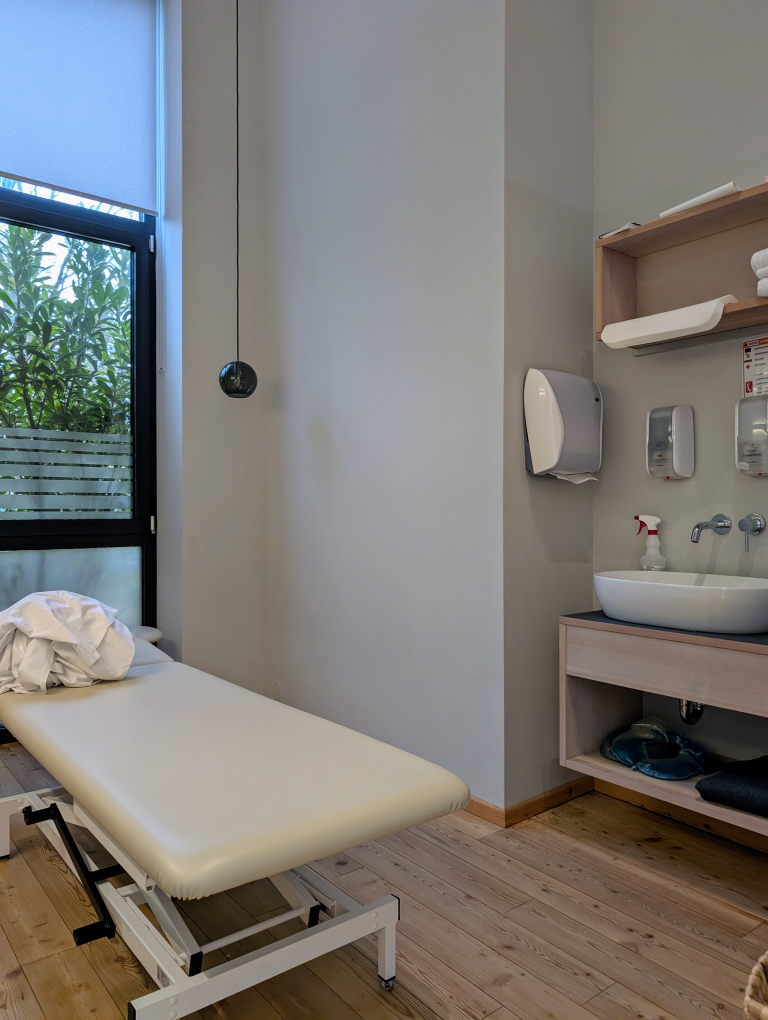 Blick in einen Raum mit Massageliege und Waschbecken