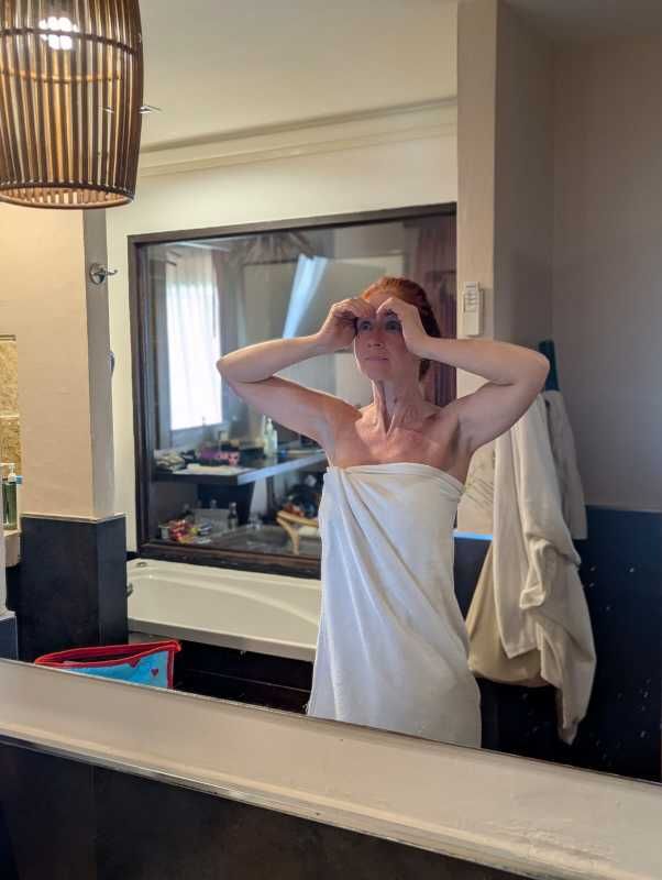 Karin steht im Badezimmer, Hände am Gesicht