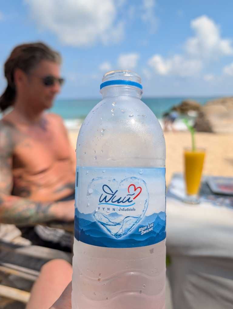 Wasserflasche, im Hintergrund Glas mit Mangoshake