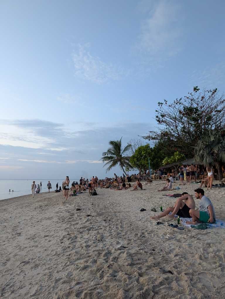 Sandstsrand bei untergehender Sonne und einigen Menschen in der Ferne