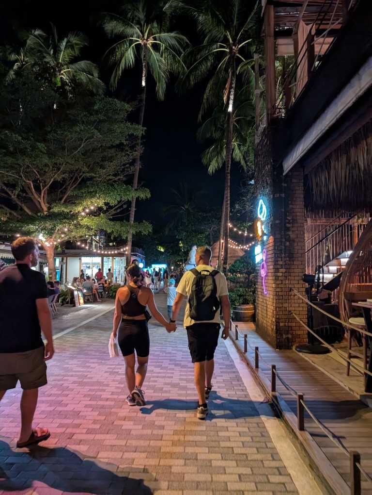 Ein Pärchen Hand in Hand von hinten beim Abendspaziergang