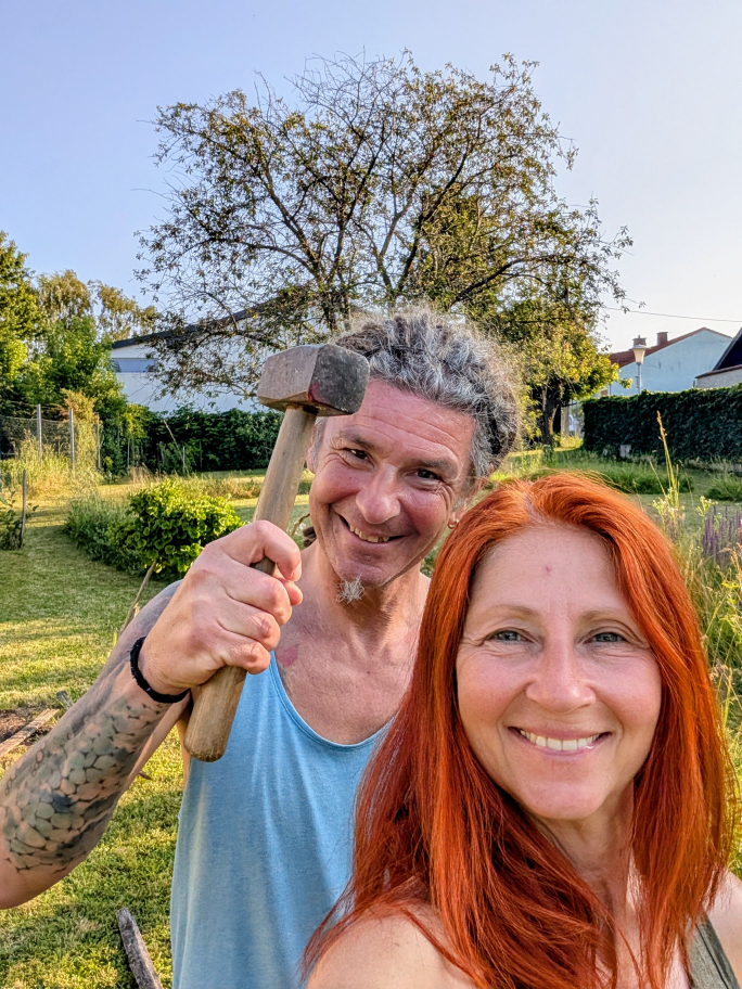 Karin und Seppi im Garten, Seppi hält einen Hammer scherzhaft über Karins Kopf