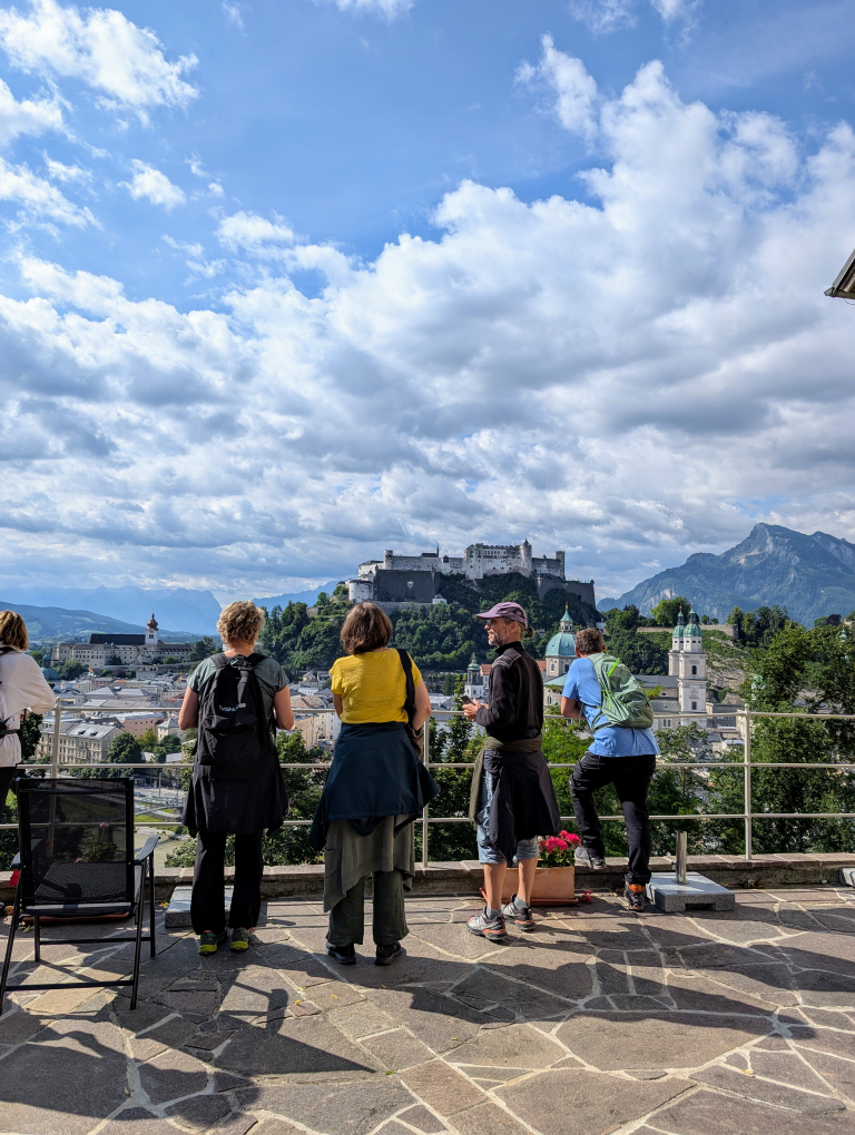 Menschen stehen auf einer Terrasse und blicken auf den Gegenüberliegend Mönchsberg