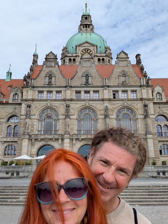Selfie von Karin und Seppi vor einem groĂen, schloĂĂ€hnlichem GebĂ€ude.