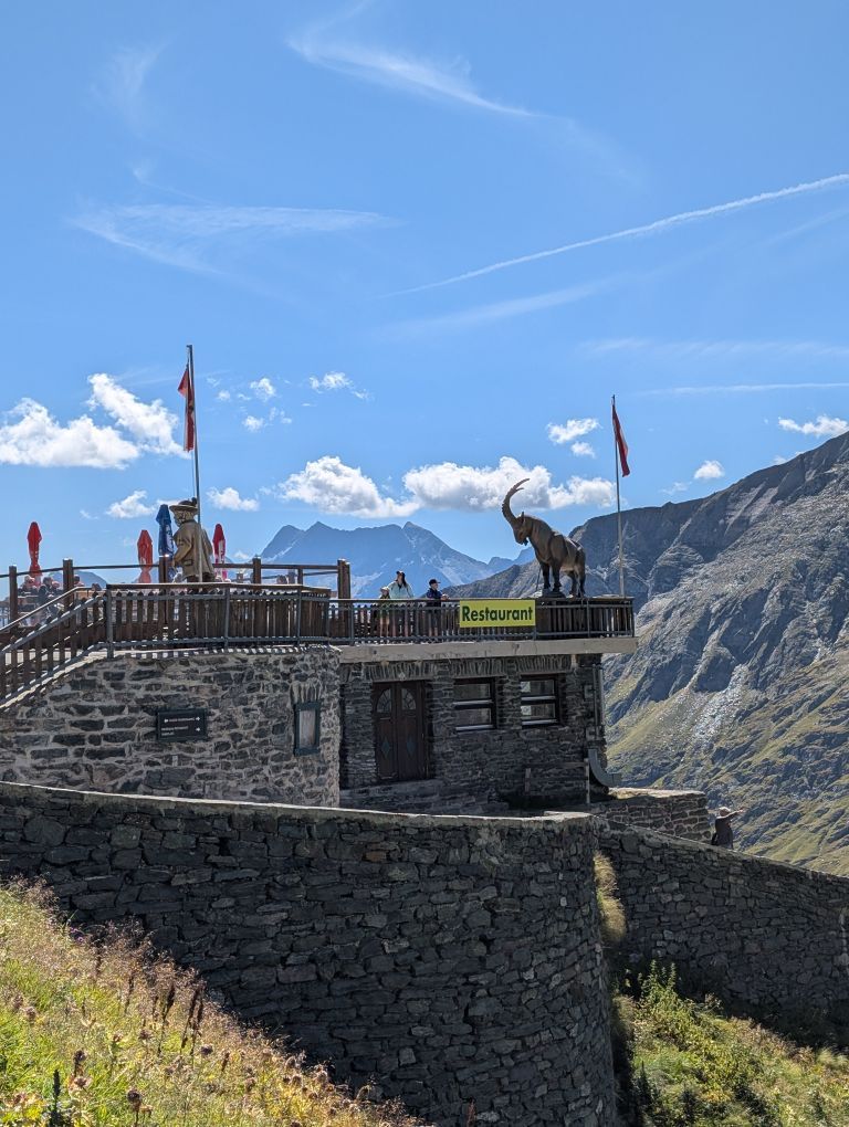 Blick auf ein großes Steingebäude mit Terrasse an einem Hang