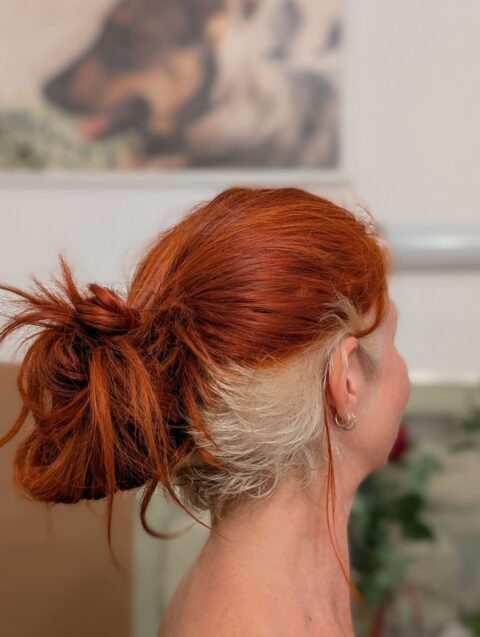 Karins Kopf von der Seite mit raufgebundenen Haaren. Der graue Undercut ist schon etwa 4 cm nachgewachsen.