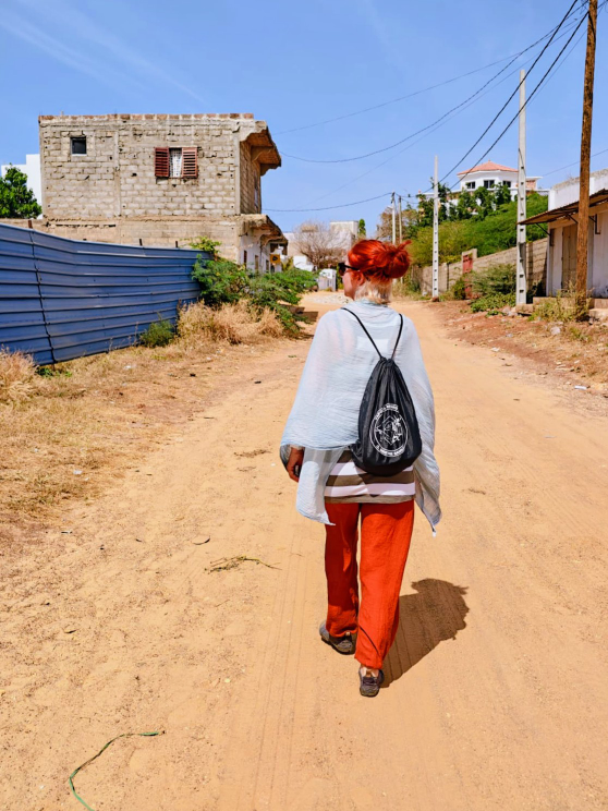 Karin von hinten, marschierend auf einer Straße aus rotem Sand