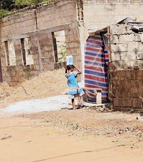 Spielendes Kind neben einer Baracke am Straßenrand