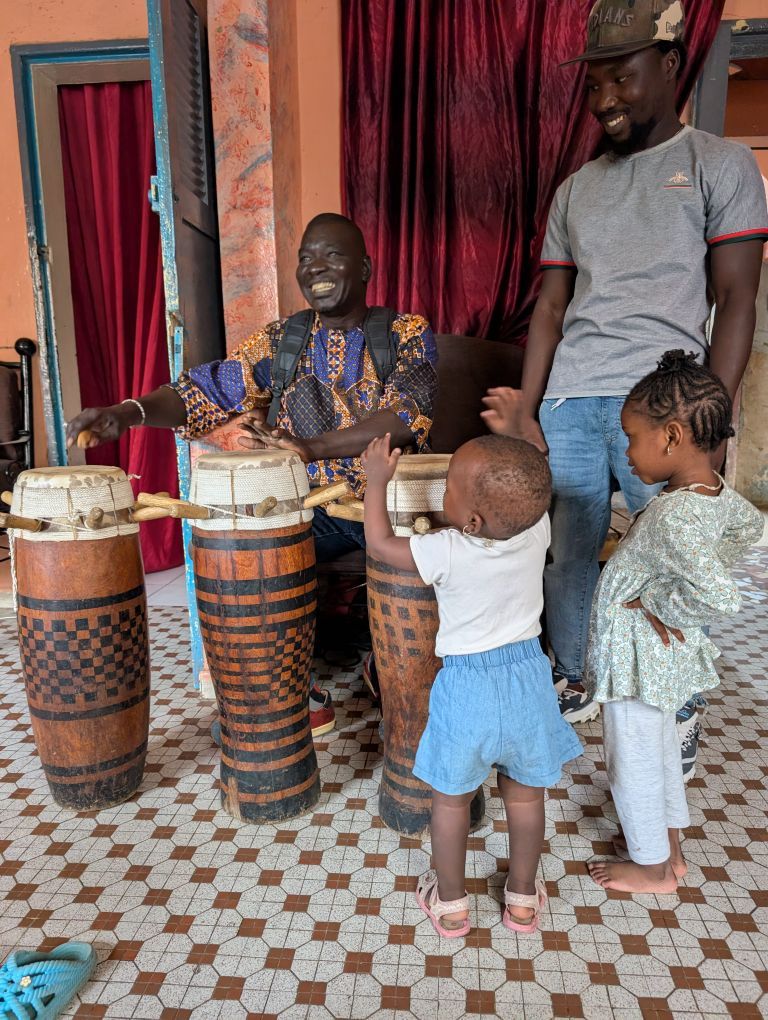 Oumar an ganz speziellen, hohen schmalen Standtrommeln, und zwei kleine Mädchen.