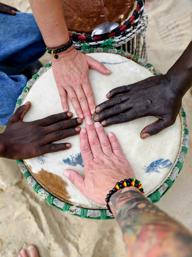 zwei weiße und zwei schwarze Hände auf einer Trommel