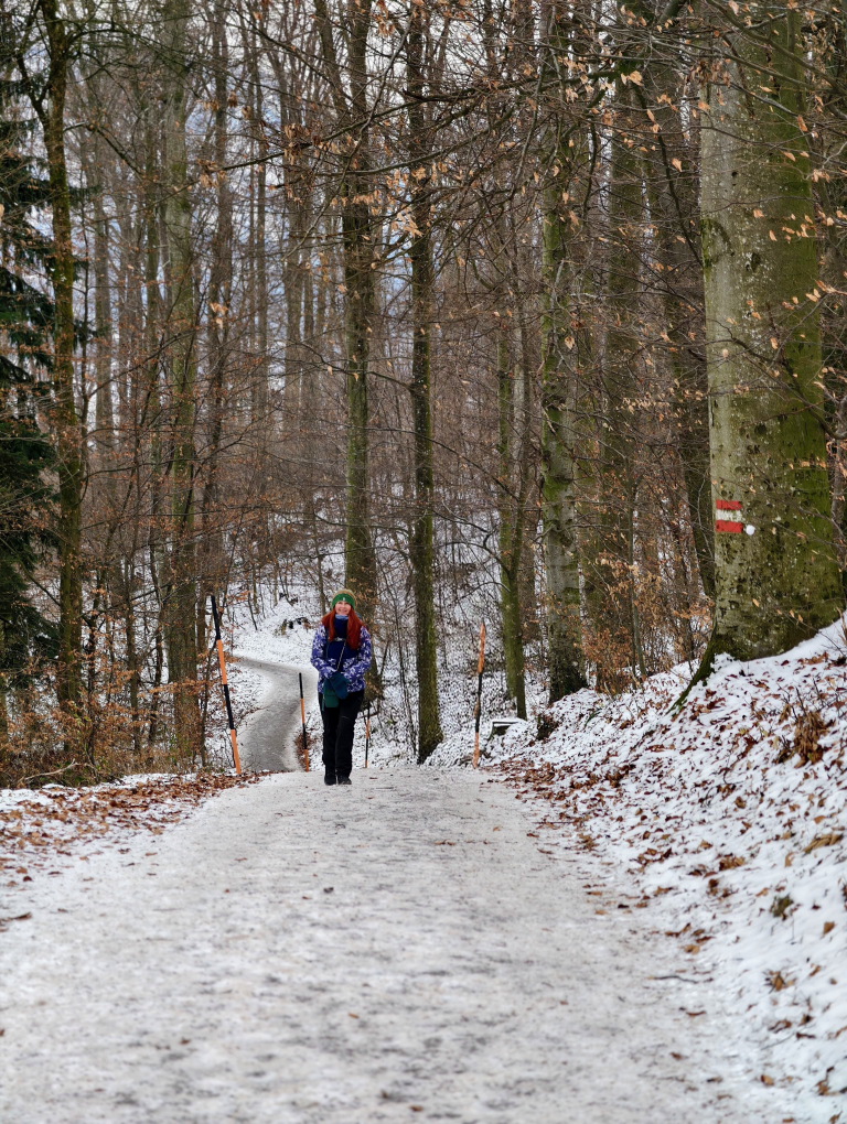 Karin, wie sie einen steilen Waldweg bergauf geht.