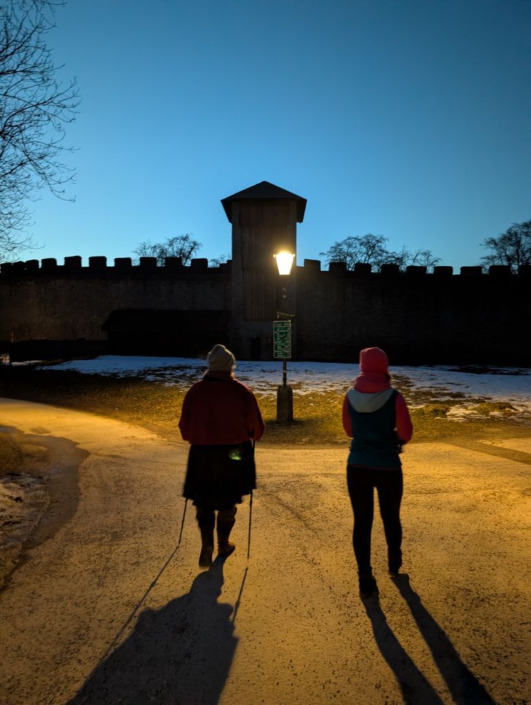 2 Frauen von hinten im Abendlicht, dahinter die Festungsmauer