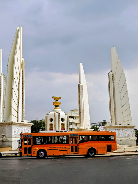 Kreisverkehr mit hohen weißen Monumenten, davor ein oranger Bus