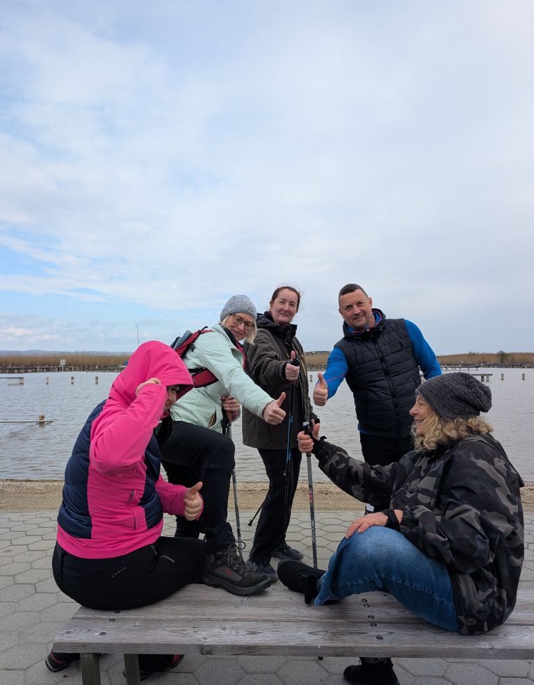 5 Menschen mit hochgestreckten Daumen, im Hintergrund ein See