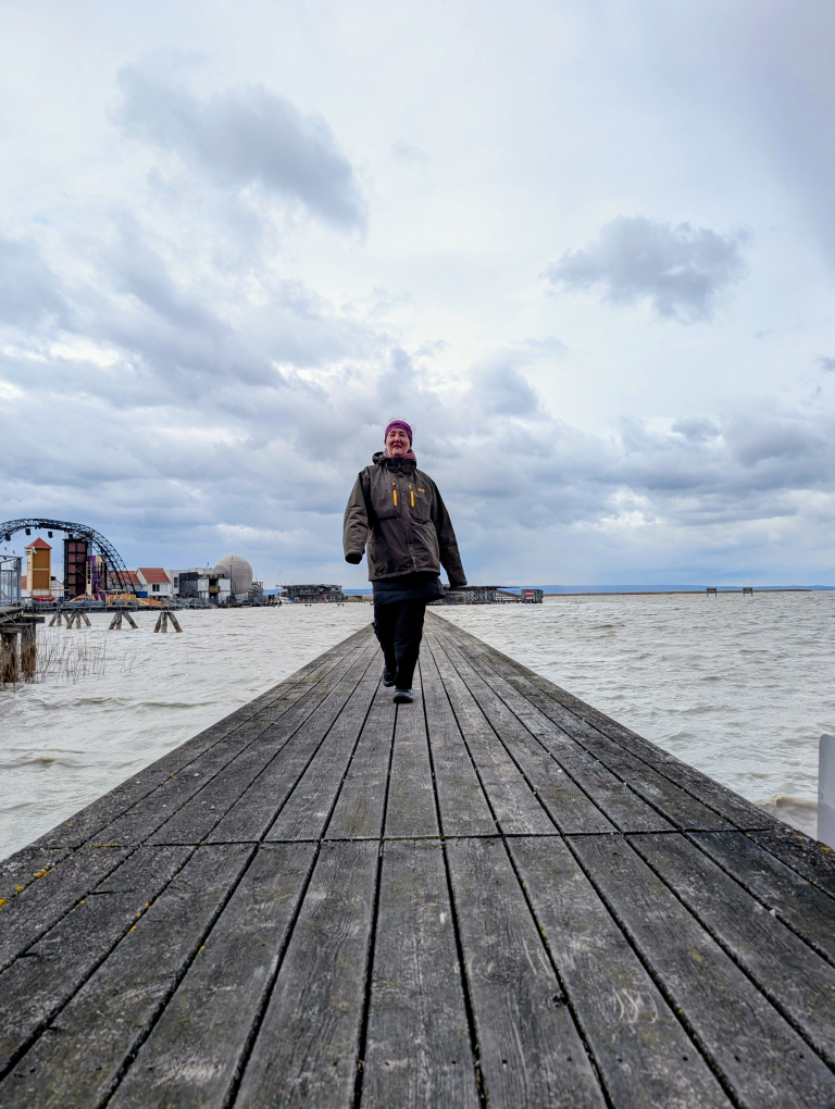 Frau stolziert über einen Holzsteg am See