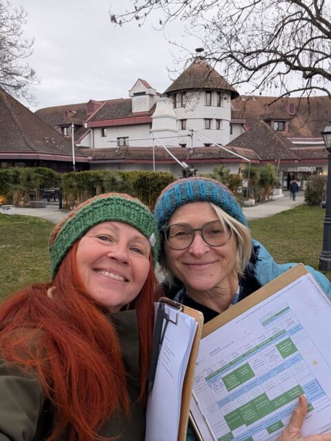 Karin und Maria, beide mit Wollmütze und Klemmbrett