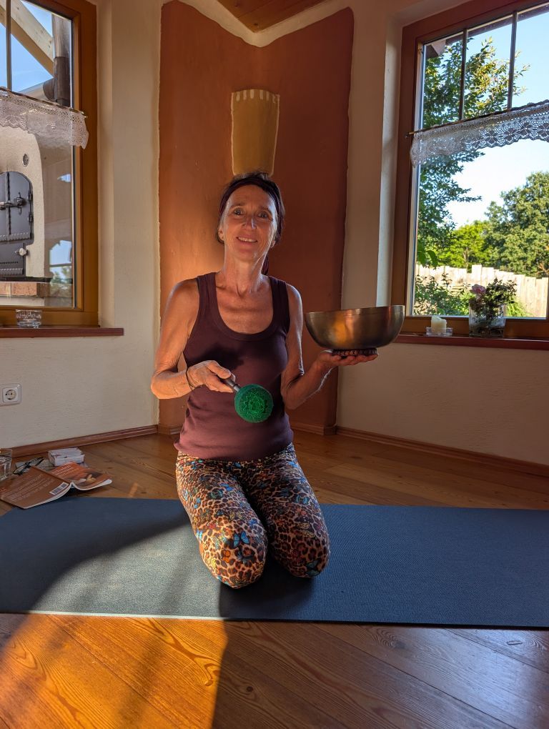 Claudia knieend auf ihrer Yogamatte mit Klangschale