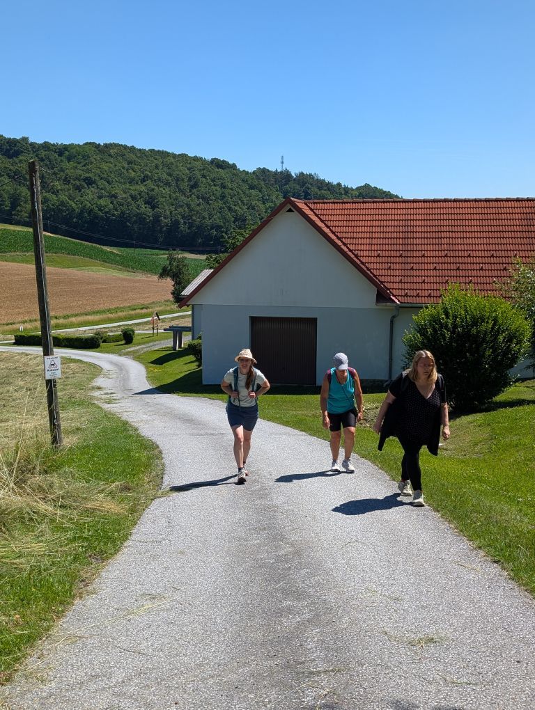 Menschen gehen auf einer sonnigen Straße steil bergauf