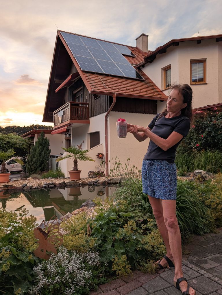 Claudia steht vor dem Teich, im Hintergrund das Haus.